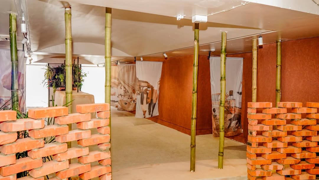 MatriAér Lab exhibition entrance with woven brick walls, bamboo columns and hanging textile portraits