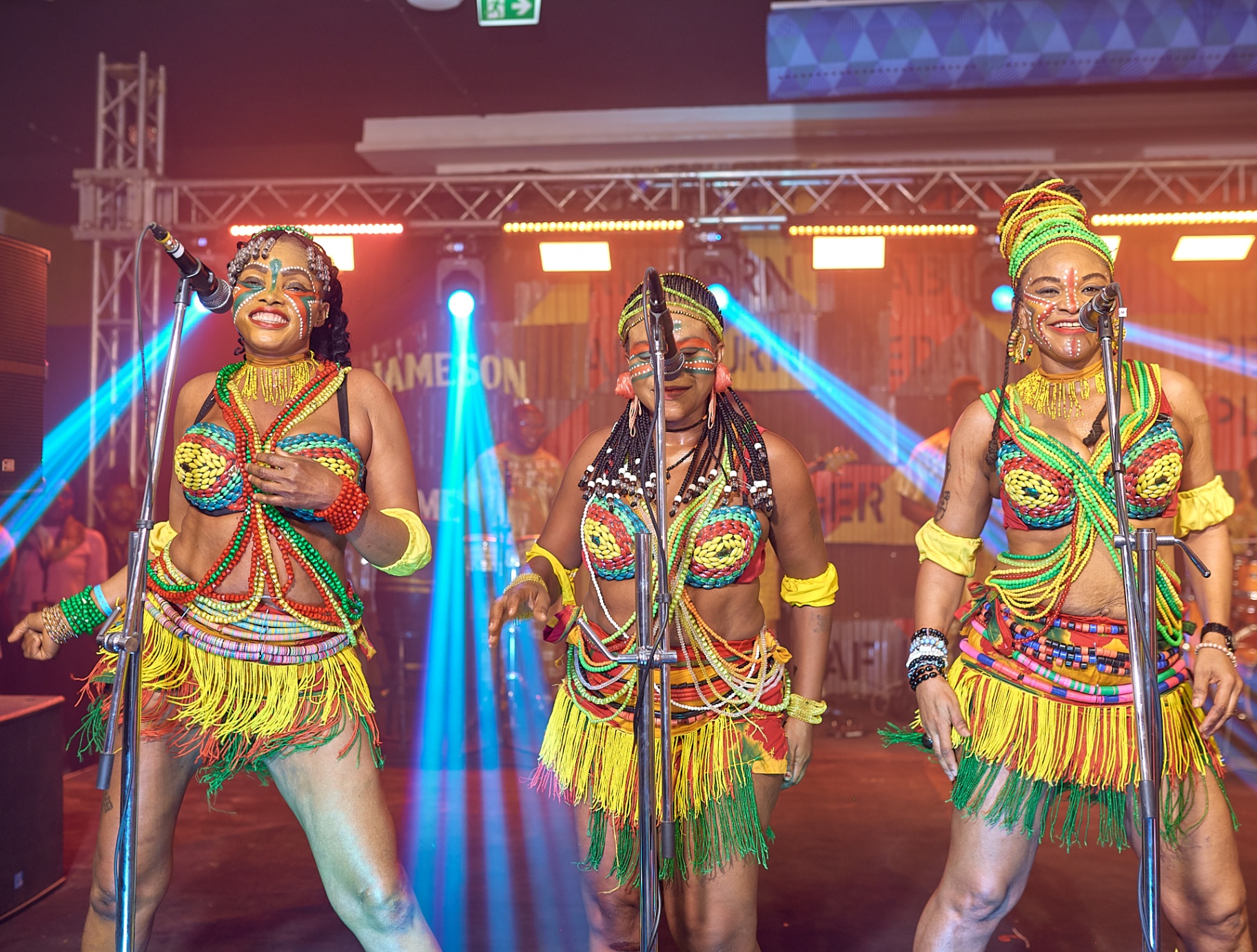 Trio of dancers in beaded costumes performing on stage at Afrobeat Rebellion