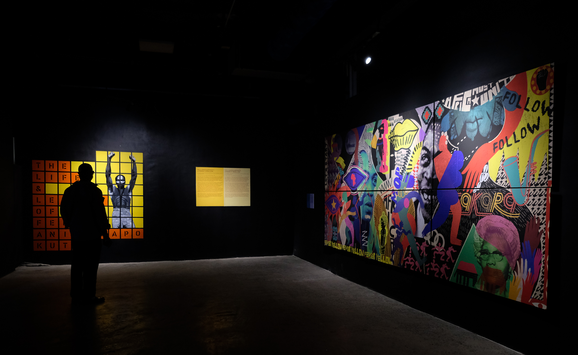 Visitor silhouetted before the Life & Legacy of Fela Anikulapo-Kuti wall and a large collage mural at Afrobeat Rebellion