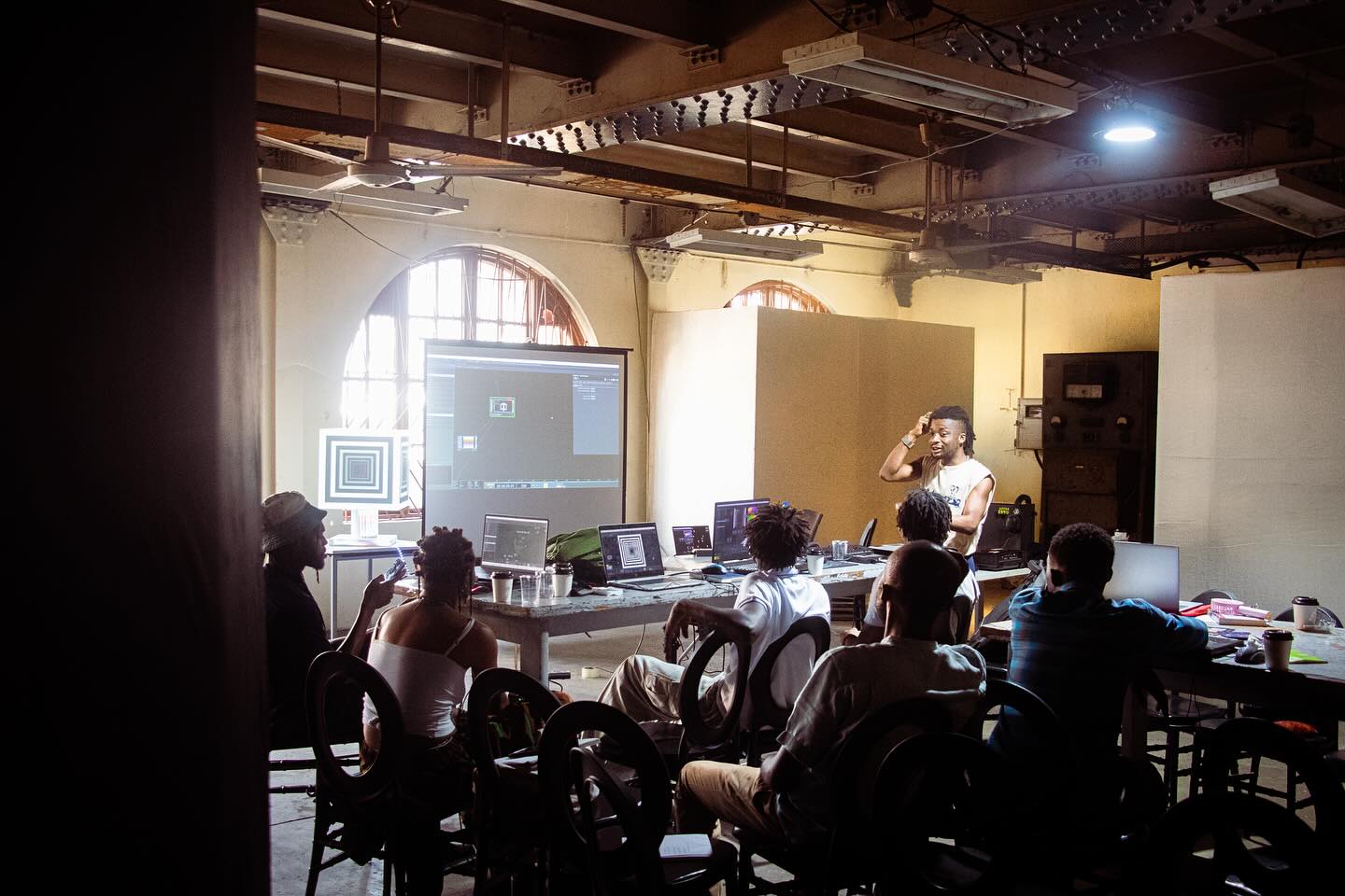 Creative technologists working across laptops and a large projected interface during the Kedu Lagos public programme