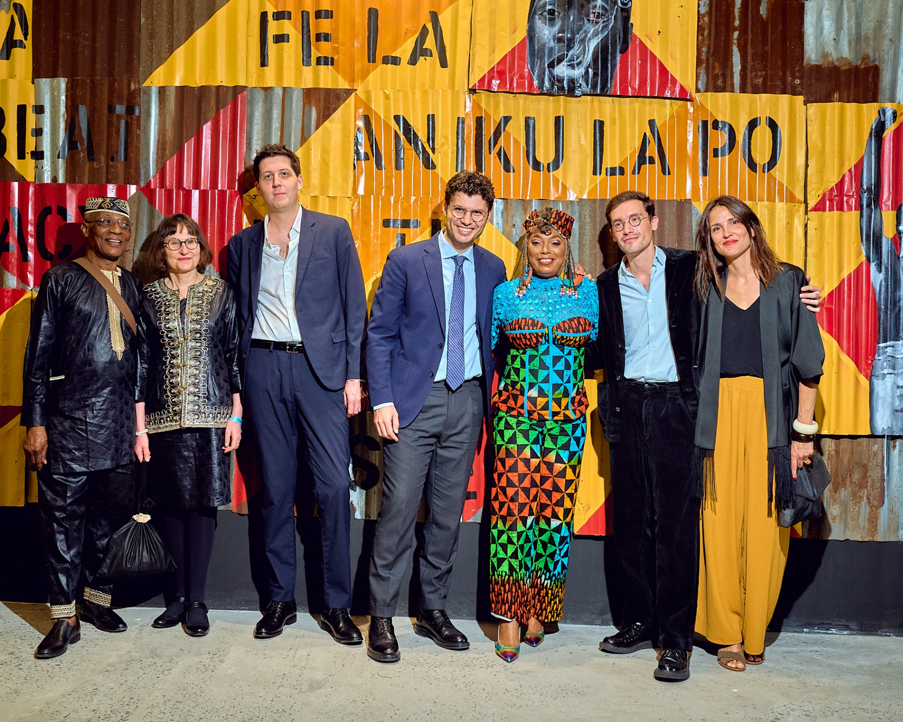 Group portrait in front of the corrugated-metal Fela Anikulapo-Kuti mural at Afrobeat Rebellion