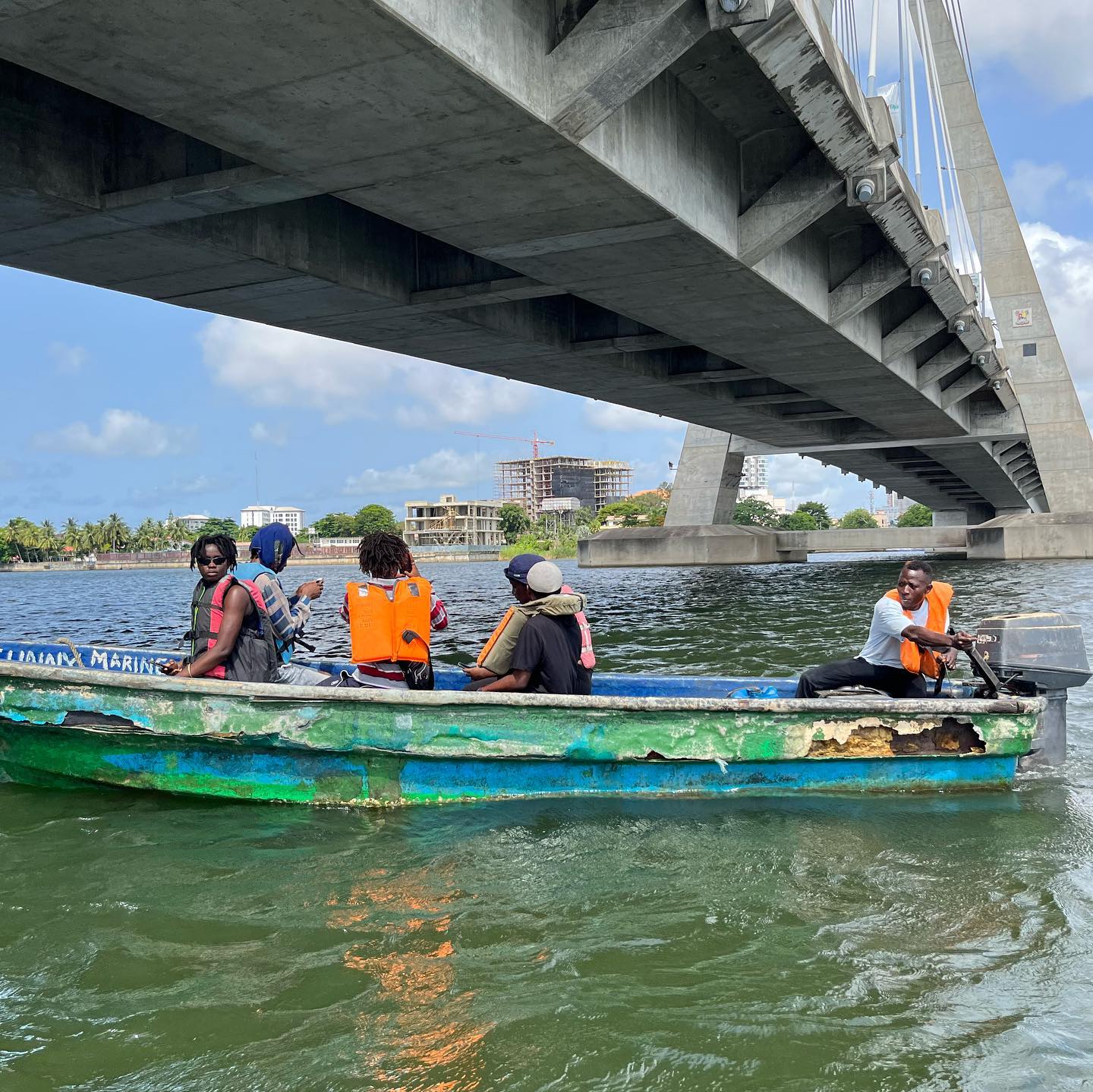 Participants crossing the Lagos Lagoon by boat under the Lekki–Ikoyi Link Bridge during a site visit