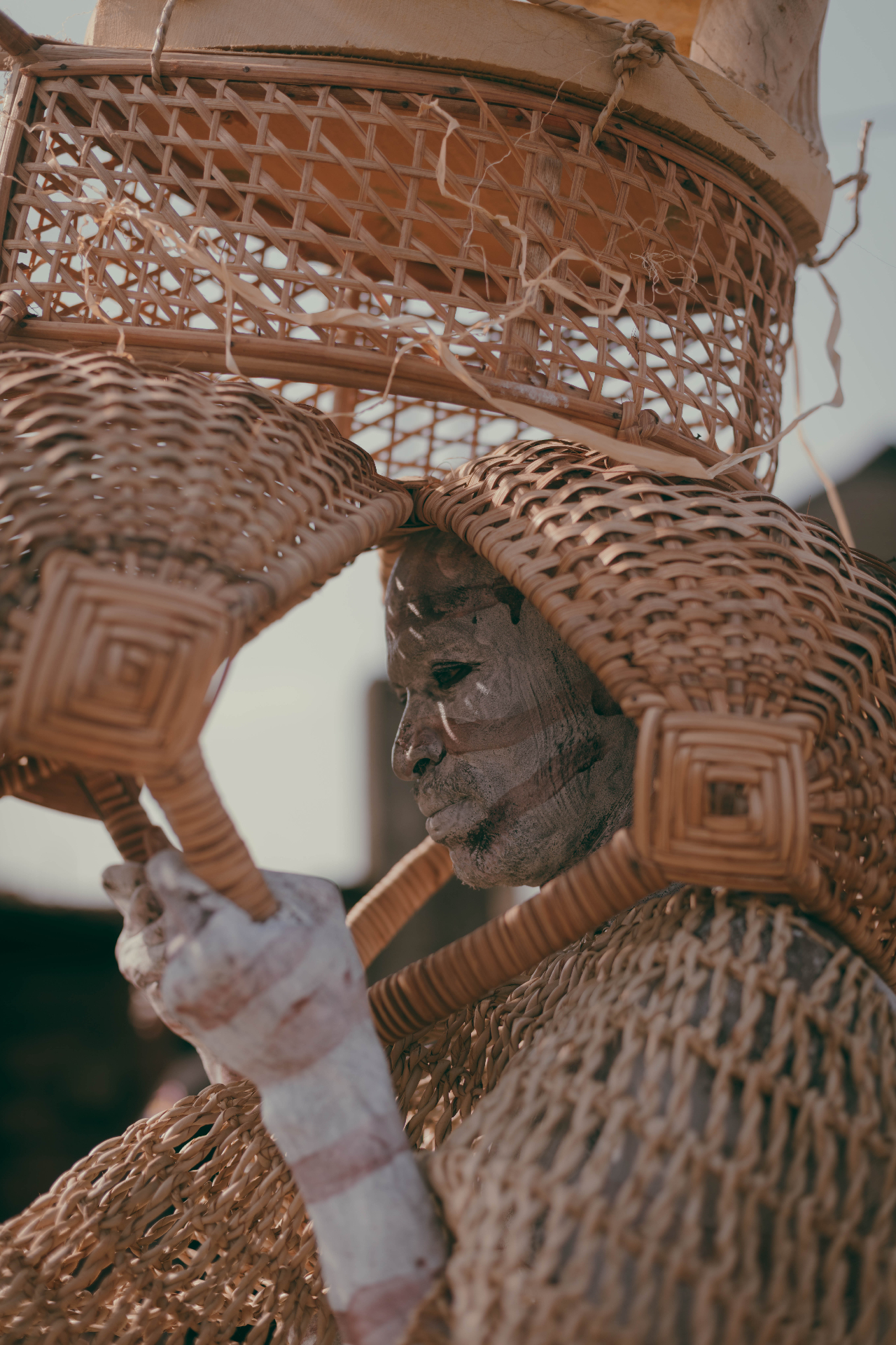 Performer in woven basket costume with painted face