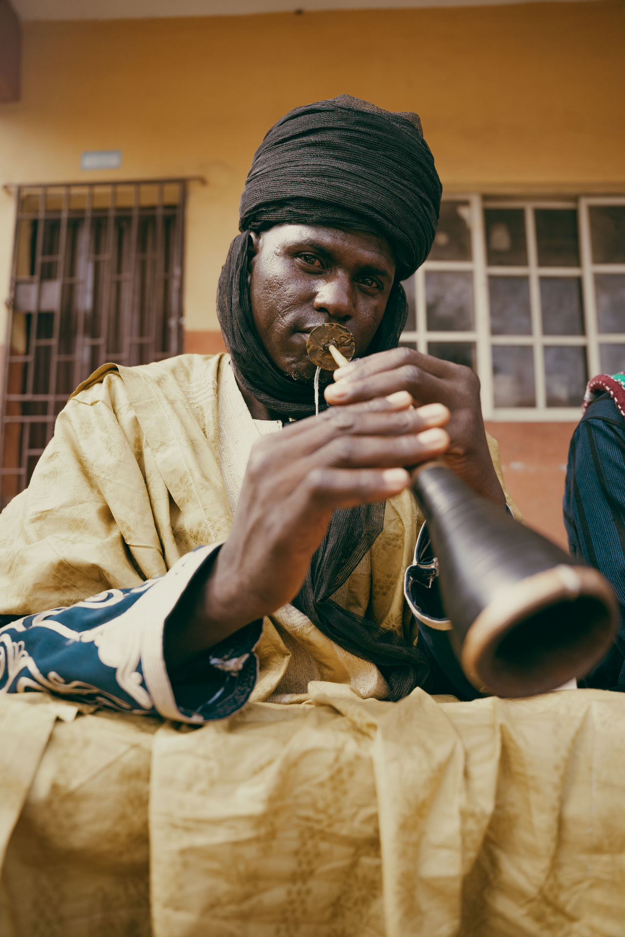 Musician playing a traditional horn in northern Nigerian attire