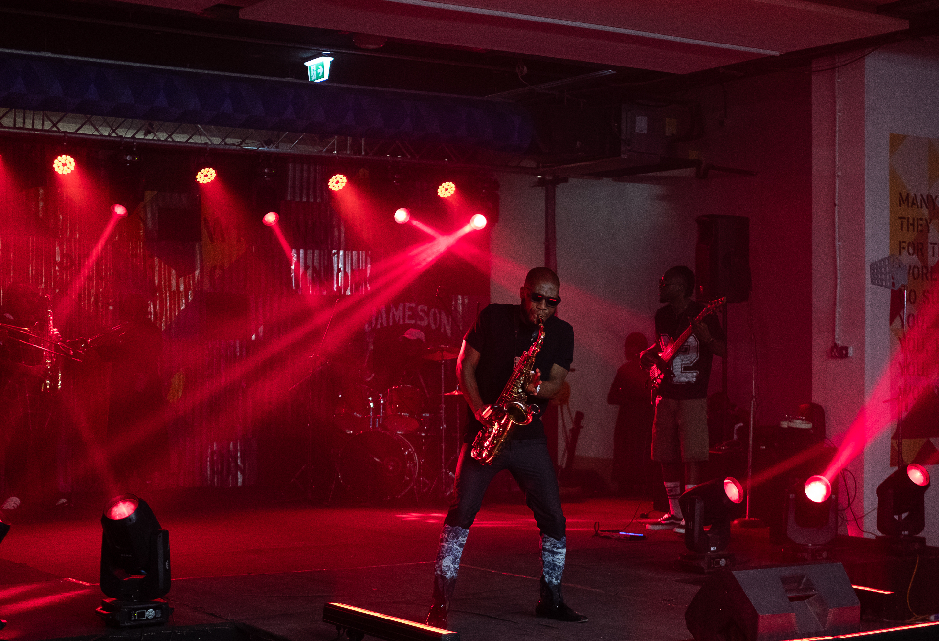 Saxophonist performing a solo under red stage lights on the Jameson stage at Afrobeat Rebellion