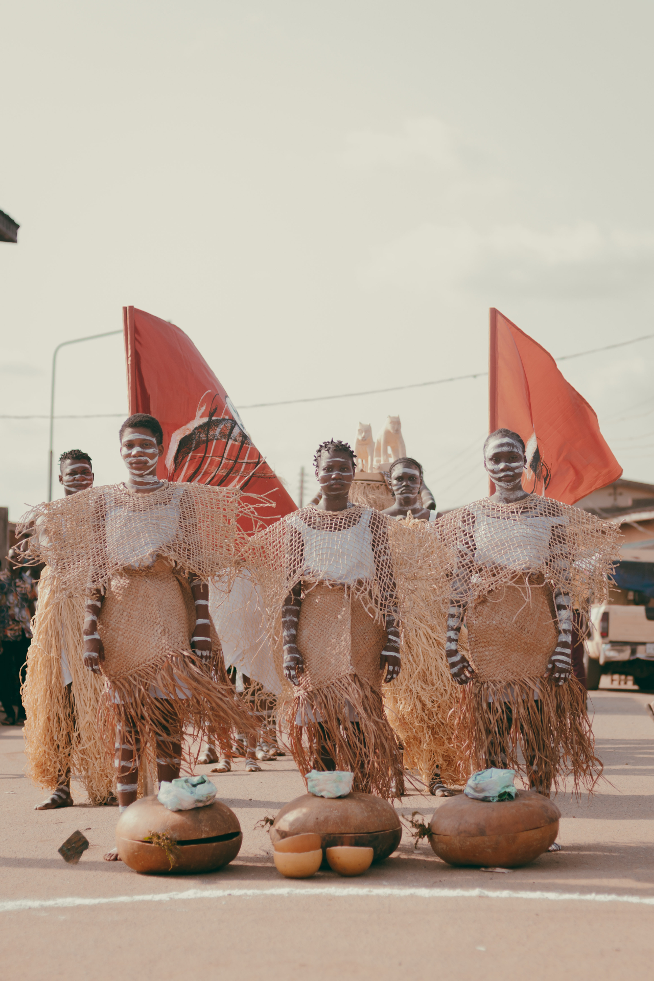 Performers in raffia costume with red flags on the street