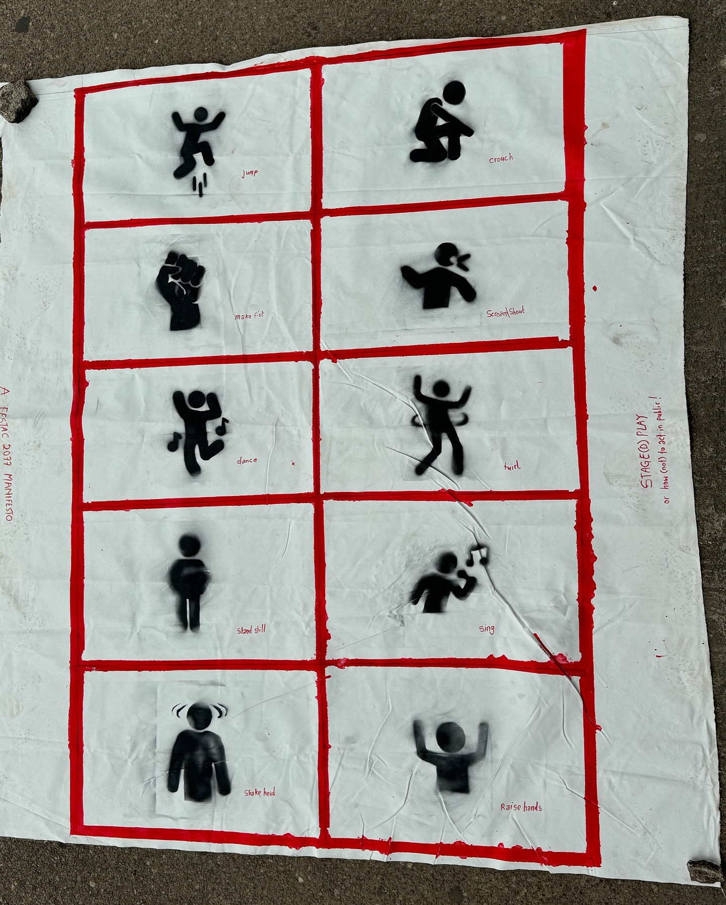 A FESTAC 2077 Manifesto, spray-stencilled 'Stage(d) Play' banner of bodily instructions: jump, crouch, make fist, scream, dance, twirl, stand still, sing, shake head, raise hands
