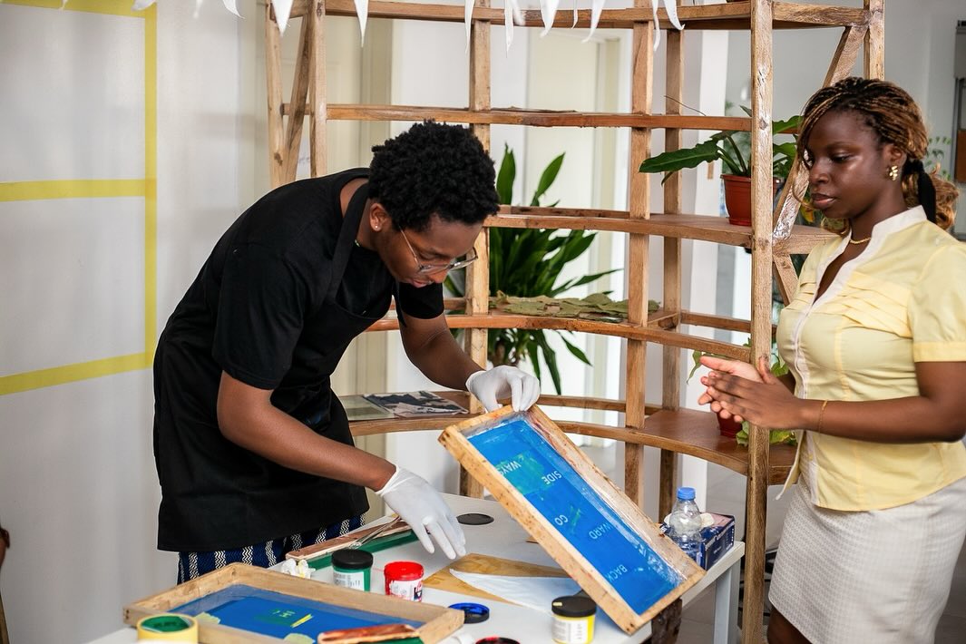 Two participants screen-printing text onto pennants during the FESTAC 2077 workshop